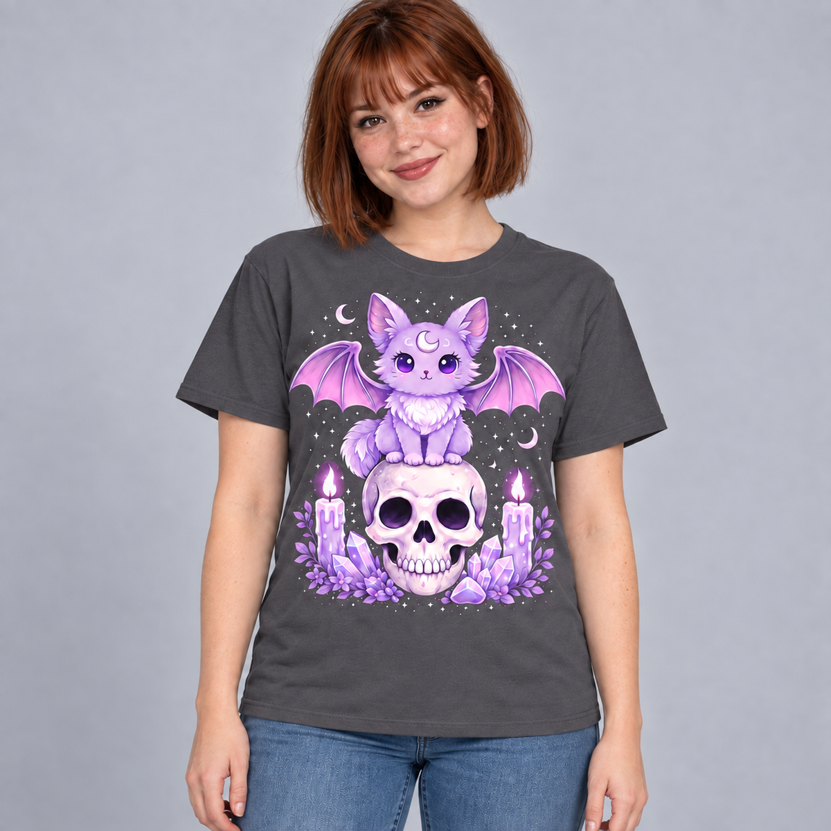 Illustrative mockup of a young adult woman wearing the Charcoal Lavender Bat Cat Tee with blue jeans on a gray studio background